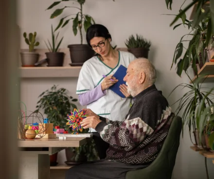 Mann am Tisch mit Pflegerin